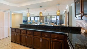A kitchen with dark wood cabinets, a black granite countertop, and pendant lighting. - Watercrest 1710 - Sleeps 8 (Panama City Beach)