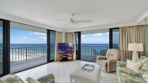 Un salón amplio con un televisor grande, asientos cómodos y un balcón con vistas a la playa.