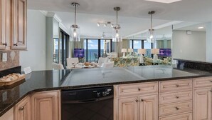 Una cocina moderna con encimeras de granito, armarios de madera y lavavajillas integrado.