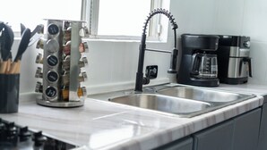 A kitchen with a double sink, a coffee maker, and a utensil holder. - Charming 3BR House, Close To The Beach (Cancún)