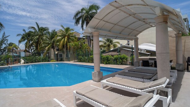 A pool area with lounge chairs and a covered pavilion. - Charming 3BR House, Close To The Beach (Cancún)