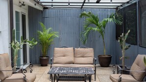 A patio with a beige sofa, two armchairs, and a metal table. There are potted plants and a blue wall in the background. - Charming 3BR House, Close To The Beach (Cancún)