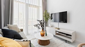 Ein modernes Wohnzimmer mit einer Couch, einem Couchtisch und einem an der Wand montierten Fernseher.