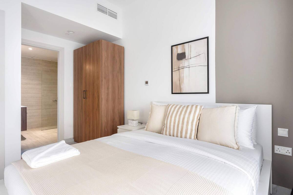 Ein modernes Schlafzimmer mit einem großen Bett, einem Holzschrank und einem minimalistischen Wandbild.