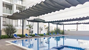 Ein Swimmingpool mit blauen Fliesen, umgeben von Liegestühlen und beschattet durch eine Markise.