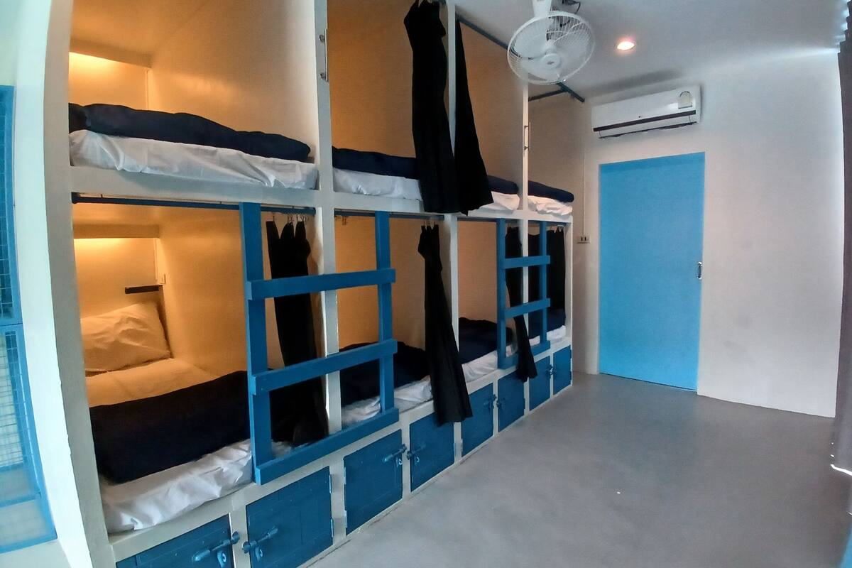 A bunk bed room with a ceiling fan, an air conditioning unit, and a blue door.