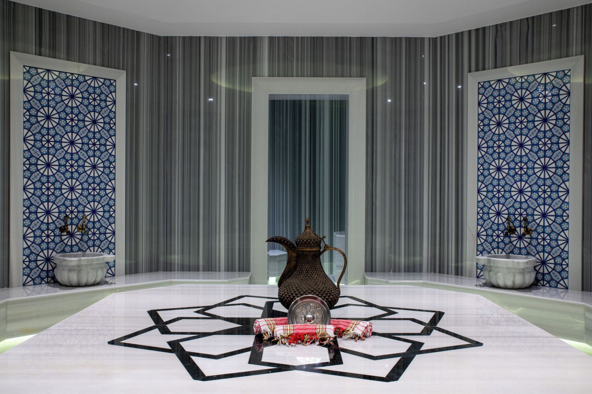 Una habitación con piso estampado, un jarrón decorativo y dos lámparas fijadas a la pared.