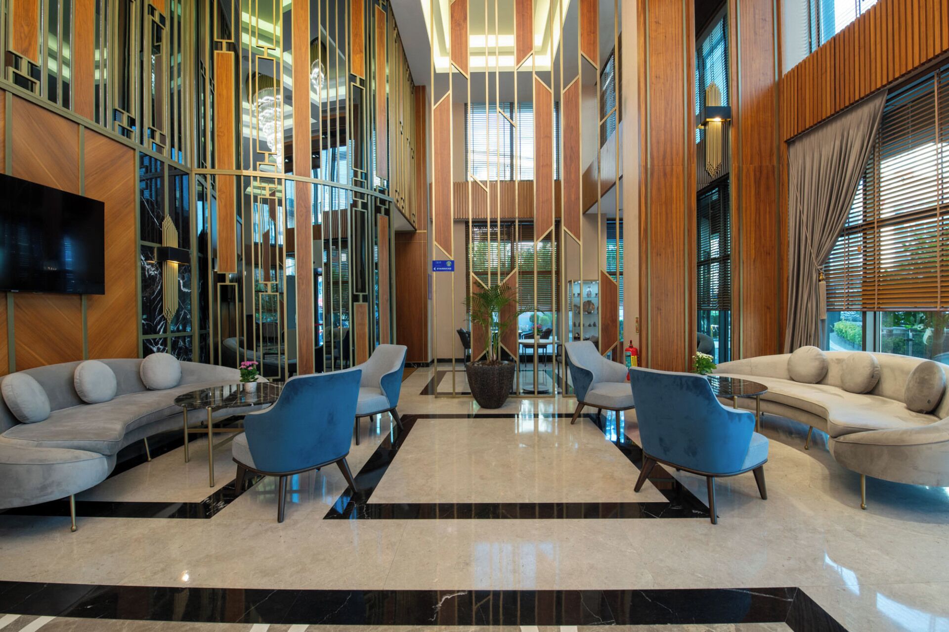 A modern lobby with a TV, seating areas, and a large window.