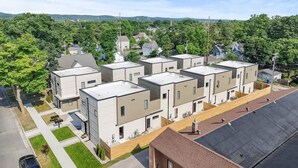 Un moderno complejo de apartamentos con varias edificaciones, un área de estacionamiento y vistas de la vegetación circundante.