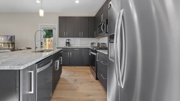 Una cocina moderna con armarios oscuros, electrodomésticos de acero inoxidable y una isla grande.