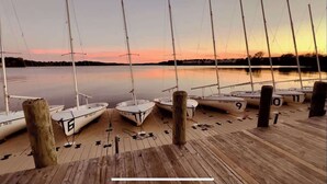 Un muelle de madera con veleros anclados al final, identificados con números.