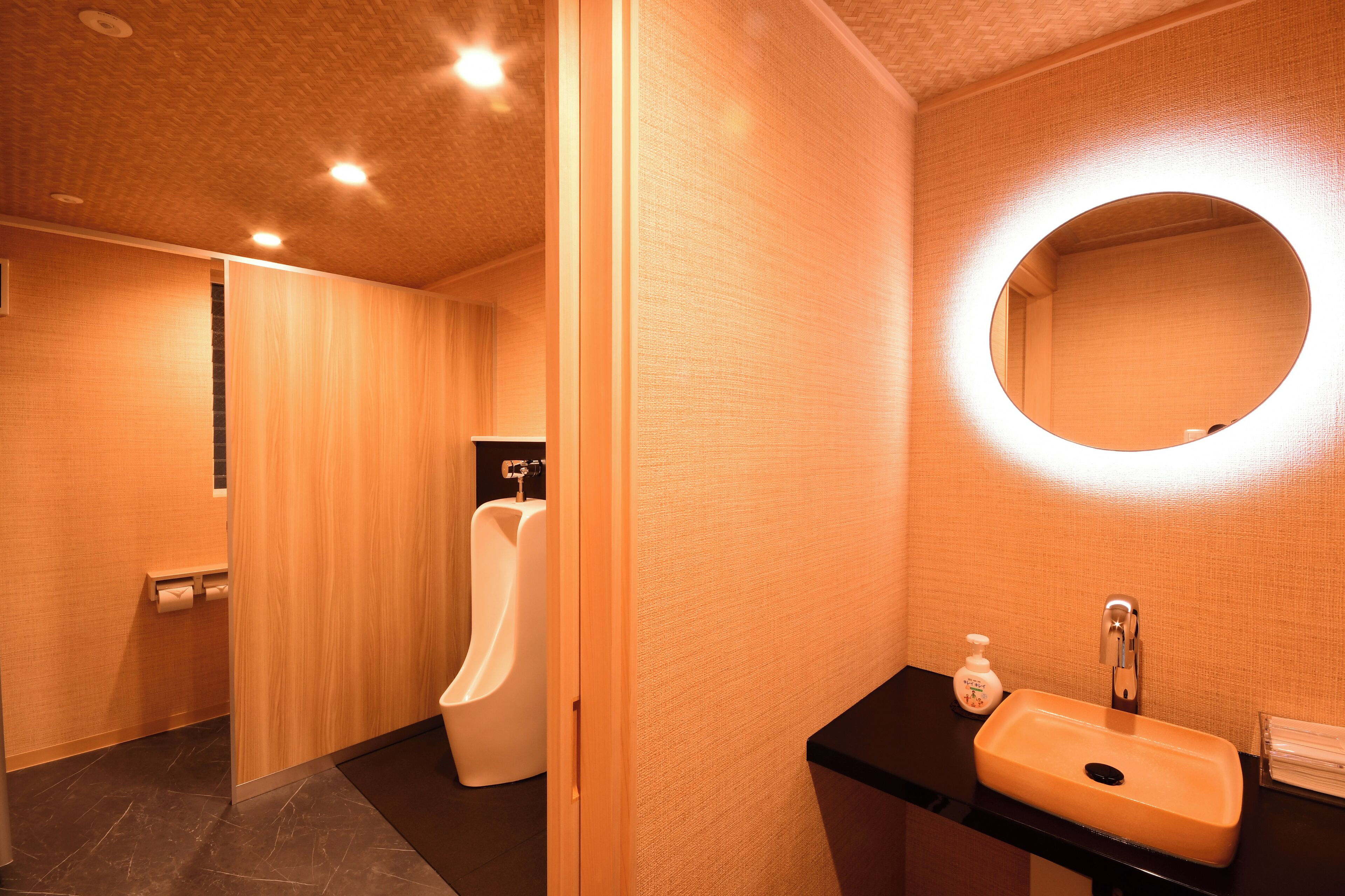 A modern bathroom with a urinal, a sink with a mirror, and a towel rack.