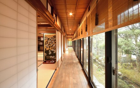 A corridor with wooden flooring and a view of a garden through large windows.