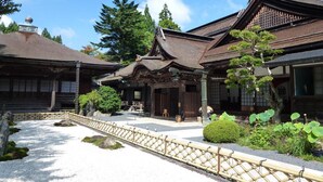 Un edificio japonés tradicional con estructura de madera, tejado de tejas y un farol de piedra.