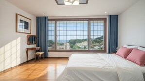 A hotel room with a large window, a bed, a desk, and a chair. - Ganghwado Happyvilly Pension (Incheon)
