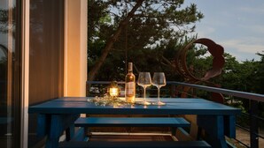 An outdoor table with a bottle and two glasses, set against a backdrop of trees and a metal sculpture. - Ganghwado Happyvilly Pension (Incheon)