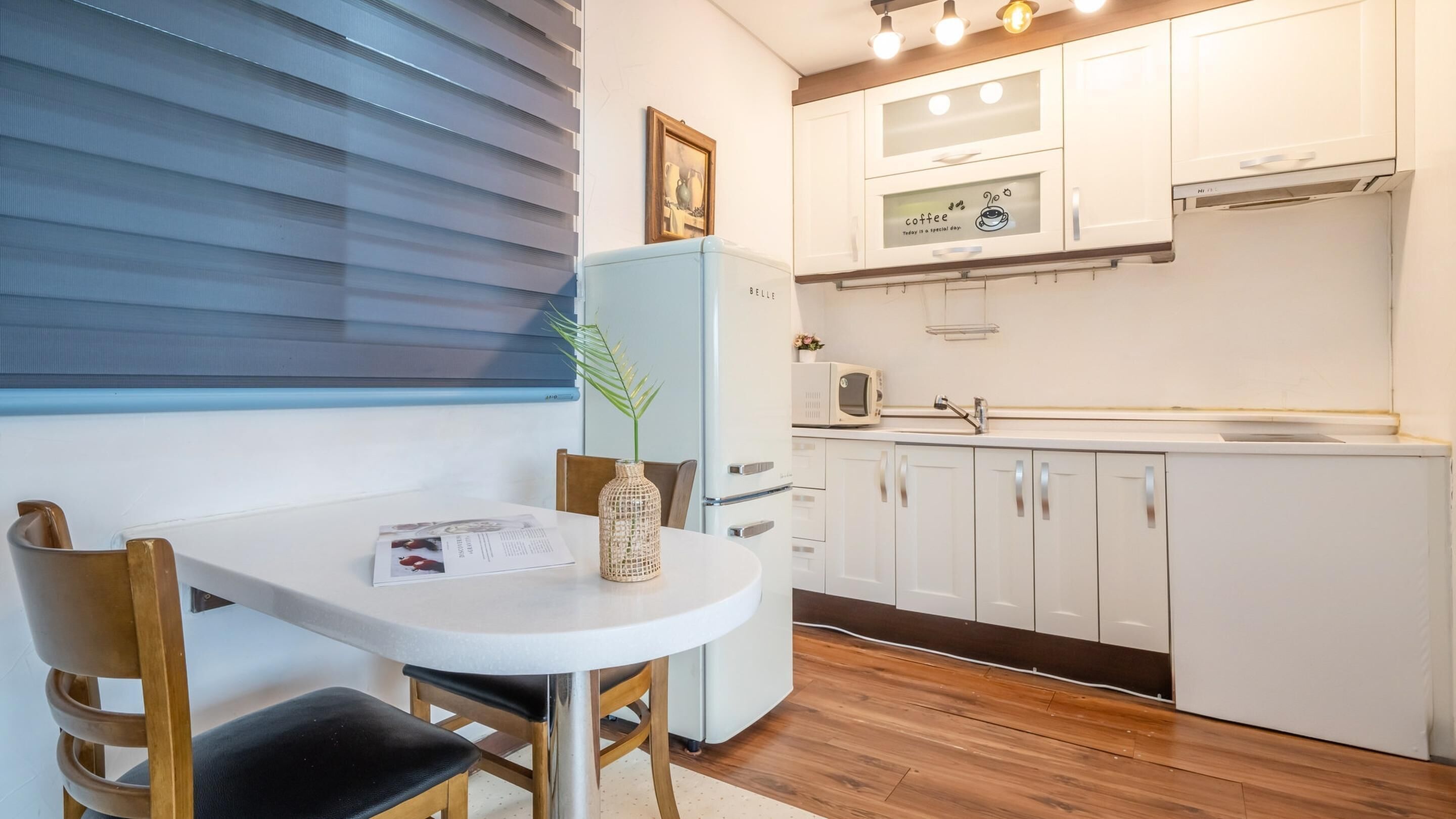A compact kitchen with white cabinets, a refrigerator, and a dining area with a table and chairs.
