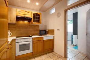 Une cuisine avec des meubles de rangement en bois, un four à micro-ondes, un four traditionnel et un évier.
