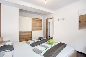 Une chambre à coucher moderne avec un lit, une tête de lit en bois, un miroir et un luminaire fixé au mur.