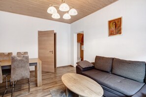 Un salon moderne avec un plafond en bois, un canapé gris, une table à manger en bois avec des chaises et un tableau accroché au mur.