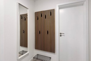 Een badkamer met een wand van houten latten, een spiegel en een deur.