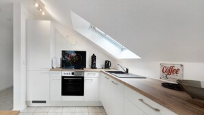 Een moderne keuken met witte kasten, een houten aanrecht, een vaatwasser, een oven en een dakraam.