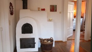 Ein Zimmer mit Kamin, Holzkorb und einer Tür zu einem anderen Raum.