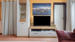 A living room with a flat-screen TV, a glass cabinet, and a door.