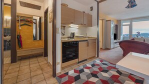 A compact kitchen with wooden cabinets, a built-in oven, and a dining area with a table and chairs.