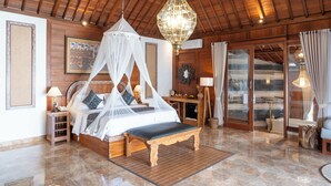 Une chambre spacieuse avec un plafond en bois, un lit à baldaquin, un grand lustre et une vue sur l’extérieur grâce à une porte vitrée.