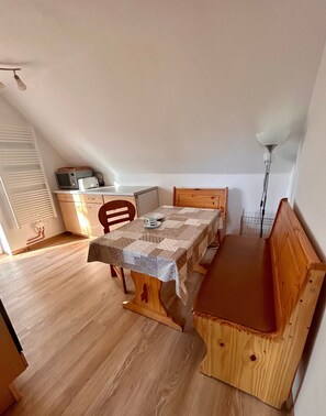 A dining area with a table, chairs, a bench, and a kitchenette in the background. - Holiday Home 'Haus Seeluft' with Private Terrace, Shared Garden and Wi-Fi (Sankt Peter-Ording)