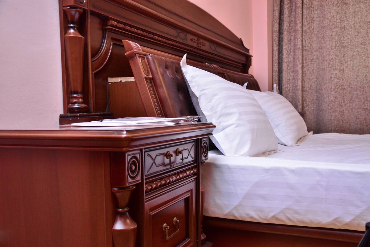 A wooden bed with white bedding and a nightstand with drawers.