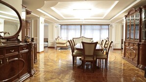 A spacious dining area with a round table and chairs, a large wooden cabinet, and a mirror on the left. - Karvan-N (Tashkent)