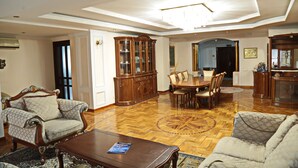 A spacious living room with a wooden dining table, two armchairs, a coffee table, and a large cabinet. - Karvan-N (Tashkent)