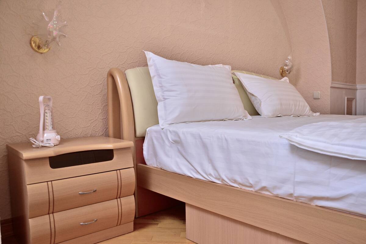 A bedroom with a bed, a nightstand, and a wall-mounted light fixture.