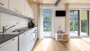 A modern kitchen with white cabinets, a black countertop, and a wooden ceiling.