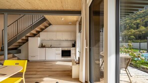 A modern kitchen with white cabinets, a wooden staircase, and a dining area with yellow chairs.