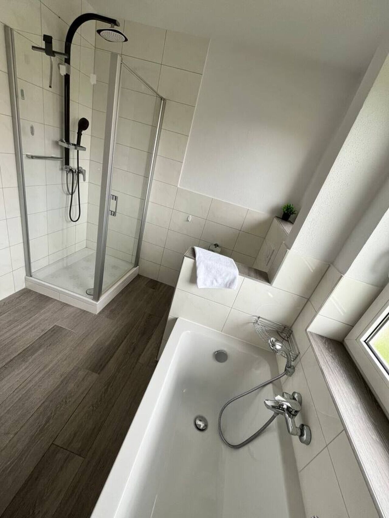 Une salle de bain moderne avec une douche à parois de verre, une baignoire sur pieds et une petite fenêtre.