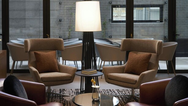 A modern lounge area with leather armchairs, a round glass coffee table, and a floor lamp. - AC Hotel by Marriott Seattle Downtown (Seattle)