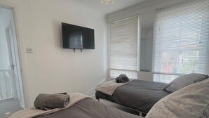 A bedroom with two beds, a flat-screen TV, and a chandelier. - Ayr Refurbished May 2024 3 Bedroom 140m2 Detached House With Private Gardens (Ayr)