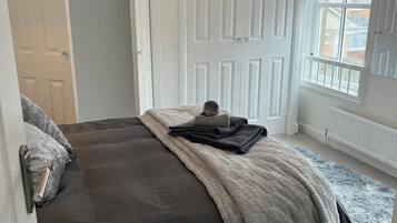 A bedroom with a bed, a door, a window, and a chandelier.