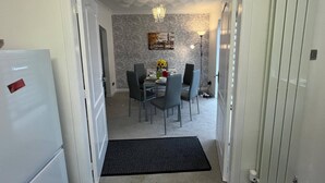A dining area with a table set for four, chairs, a chandelier, and a patterned wallpaper. - Ayr Refurbished May 2024 3 Bedroom 140m2 Detached House With Private Gardens (Ayr)