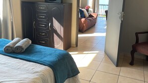 A hotel room with a bed, a wardrobe, a fan, and a view of the outside. - Wake up to gorgeous sunrises and sea views upon a wooden balcony. (Amanzimtoti)