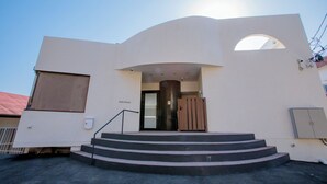 Un edificio moderno con fachada curva, una escalera que lleva a la entrada y un ventanal grande sobre la puerta.