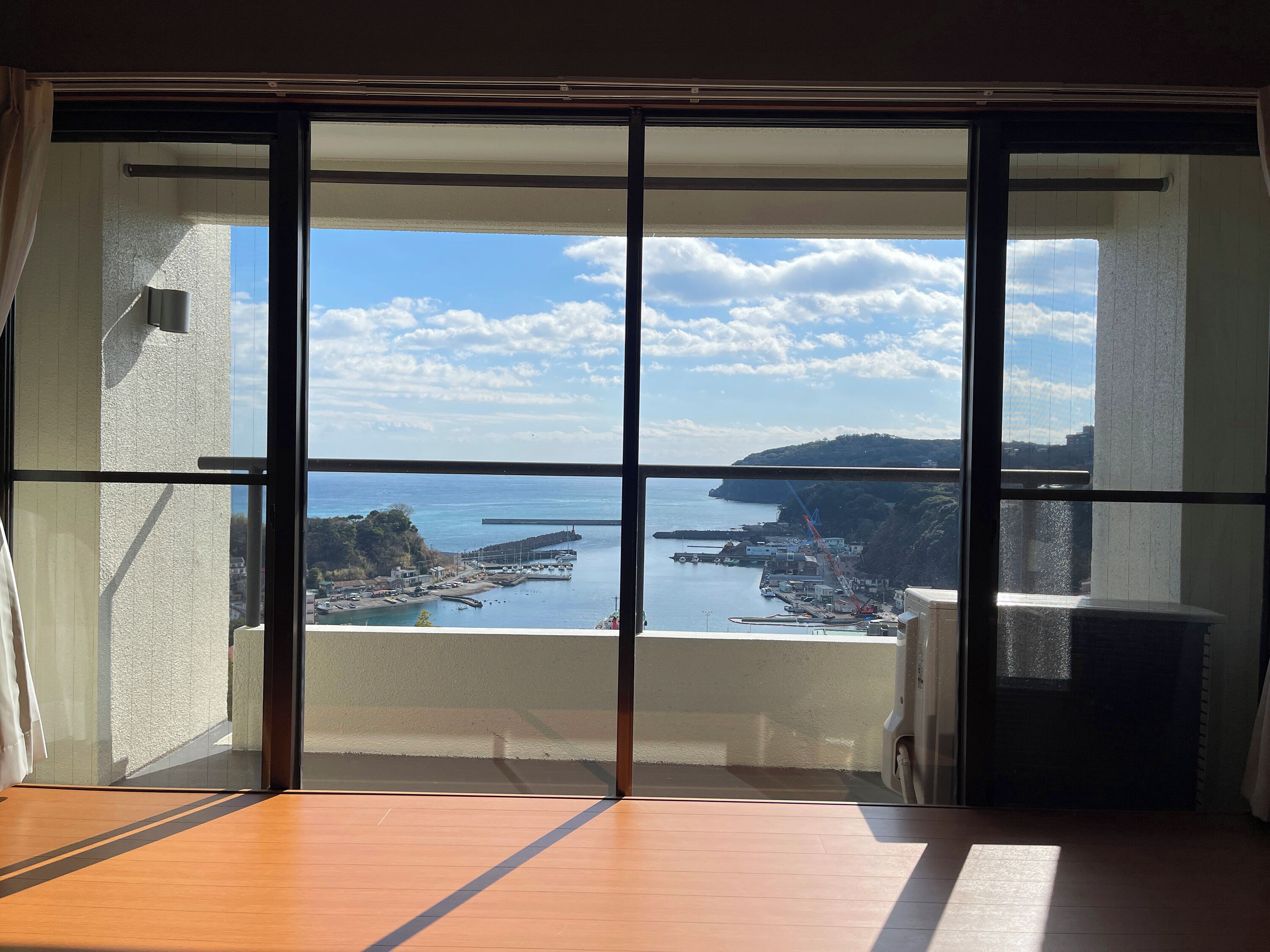 Una habitació amb un gran finestral corredís que dona a una vista costanera.