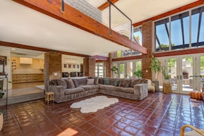 A spacious living area with a large sectional sofa, a white rug, and a rustic brick wall. - Arcadia 6BR Paradise Pool (Phoenix)