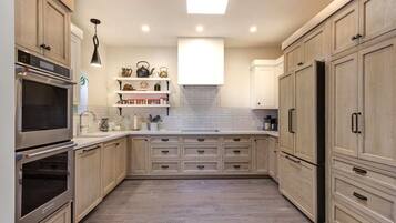 Una cocina con armarios de madera, horno empotrado y encimera con distintos utensilios.