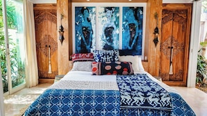 A bedroom with a large bed, ornate wooden doors, and a large abstract painting on the wall. - 353 Degrees North (Penida Island)