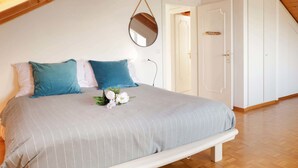Un dormitorio con cama, almohadas, un espejo y una puerta.