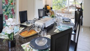 Un comedor con una mesa dispuesta para cuatro, que incluye una estación de buffet, copas de vino y un centro de mesa decorativo con una orquídea.